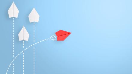 3 white paper airplanes heading north and one red paper airplane veering right