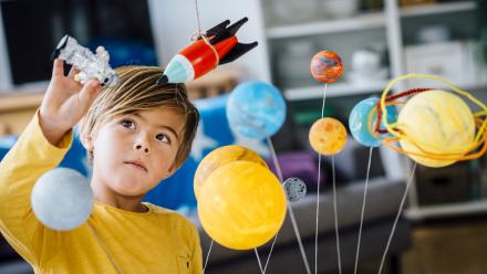 boy playing with mobile planets and spaceships within his house