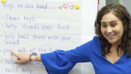 Teacher pointing to a board with writing on it.