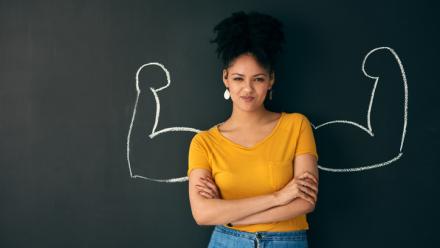 Shot of a woman posing with a chalk illustration of flexing muscles against a dark background
