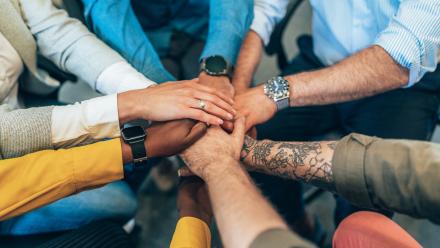 multi ethnic team holding their hands together.