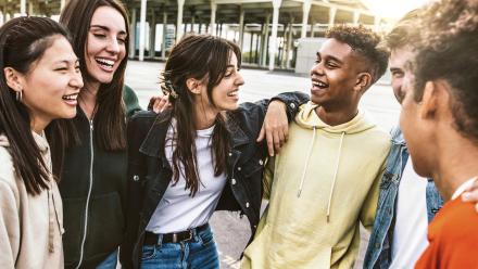 Cheerful young people walking outside talking and having fun - Mixed race friends hanging down the street - Group of teenagers having party celebrating laughing out loud