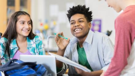 three middle school aged students laughing with one another