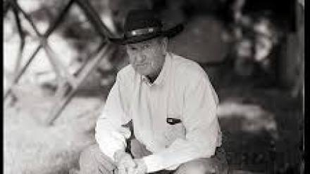 Close up of author Stuart H. Brody sitting on a bench wearing a cowboy hat.