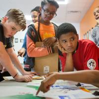 Multicultural group of middle school kids in class discussing project