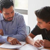Male Latino teacher discussing assessment results with male Latino student