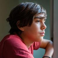 Young teen boy looking pensively out the window