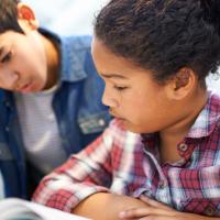 two middle school students reading a class text together