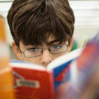 Middle school boy looking at graphic novel in the library
