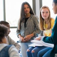 Multicultural group of teens talking about a book