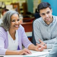 Older woman leading a conversation with younger, gentlemen colleagues