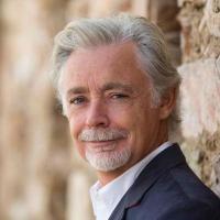 Headshot of Eoin Colfer leaning against a brick wall.
