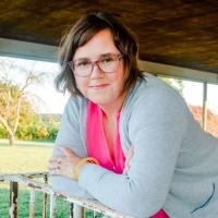 Woman leaning on a railing, smiling into the camera