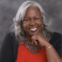 Sharon smiling to the camera with a hand under her chin