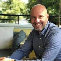 Chris Stevenson sitting on an outdoor couch, smiling to the camera
