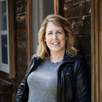 Author leaning against a window in a black jacket and jeans