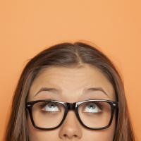 Half portrait of a young girl with glasses looking up stock photo 