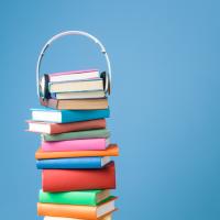 Stack of colorful books with a headset resting on the top of the stack
