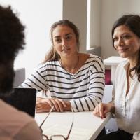 Mom and adolescent daughter meeting with a male teacher