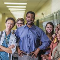 Principal surrounded by smiling high school students