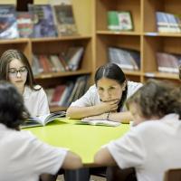 Early adolescents sitting at round table and reading their books.