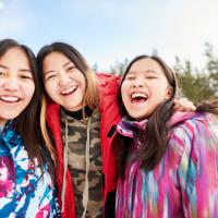 Group of three indigenous teen girls smiling into the camera