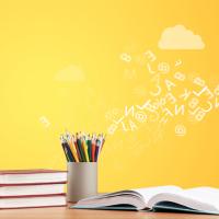 books on a table with pencils and letters scrawled across a yellow wall