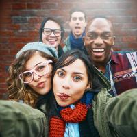 Group of five teens making silly faces and smiling into the camera