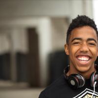 Teen boy listening to music and smiling at the camera