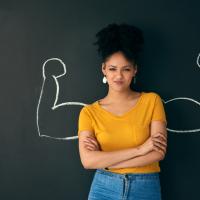 Shot of a woman posing with a chalk illustration of flexing muscles against a dark background