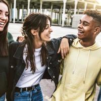 Cheerful young people walking outside talking and having fun - Mixed race friends hanging down the street - Group of teenagers having party celebrating laughing out loud