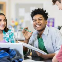 three middle school aged students laughing with one another