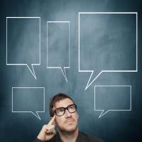 Man pointing to his head with speech boxes all around him.