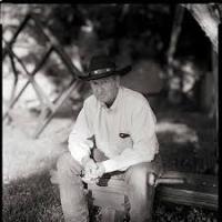 Close up of author Stuart H. Brody sitting on a bench wearing a cowboy hat.