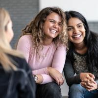 Two teen girls leaning into one another and smiling.